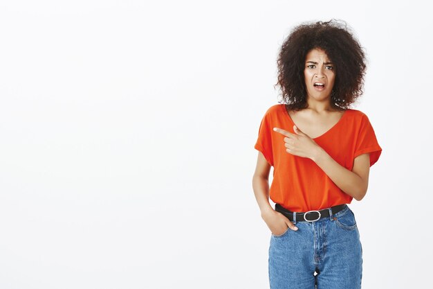 Schockierte Frau mit Afro-Frisur posiert im Studio