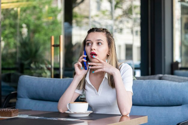 Kostenloses Foto schockierte junge dame, die im restaurant telefoniert