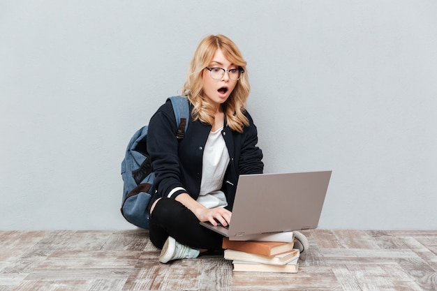 Schockierte junge Studentin mit Laptop-Computer.