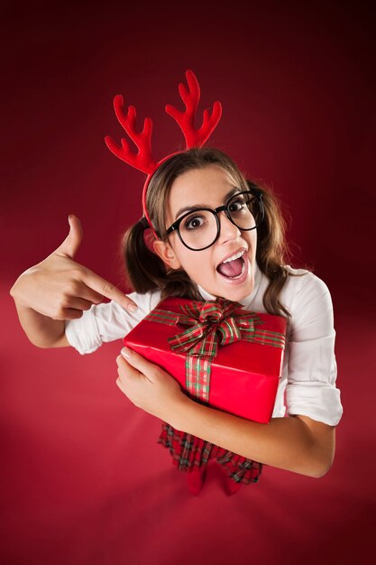 Schockierte nerdige Frau, die auf Weihnachtsgeschenk zeigt