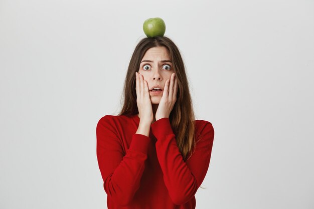 Schockierte Panikfrau mit grünem Apfelziel auf Kopf