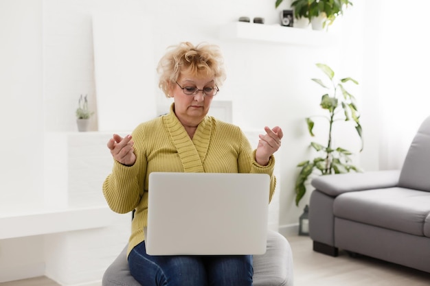 Schockierte reife frau mittleren alters, die sich gestresst fühlt, unglaubliche online-nachrichten zu lesen, überraschte ältere alte dame, die laptop anschaut, überrascht von unerwartetem festsitzendem computerproblem, sitzt zu hause auf dem sofa