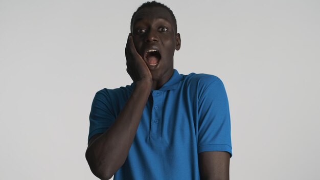 Schockierter Afroamerikaner mit offenem Mund, der überrascht aussieht, isoliert auf weißem Hintergrund Wow-Ausdruck