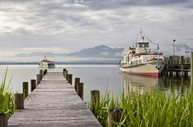 Schön von einem Holzdeck, das zum Meer mit Bergen und Schiffen auf dem Hintergrund führt