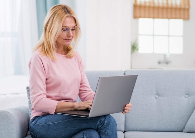 Schöne ältere Frau, die einen Laptop anhält