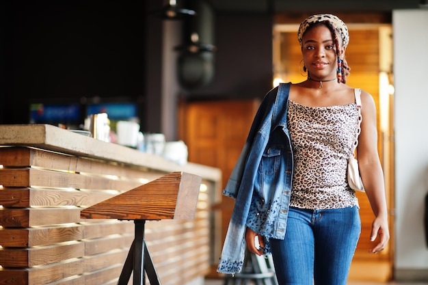 Schöne afrikanisch-amerikanische Frau mit Dreadlocks im Leoparden-Outfit im Café Schönes cooles modisches schwarzes junges Mädchen im Innenbereich