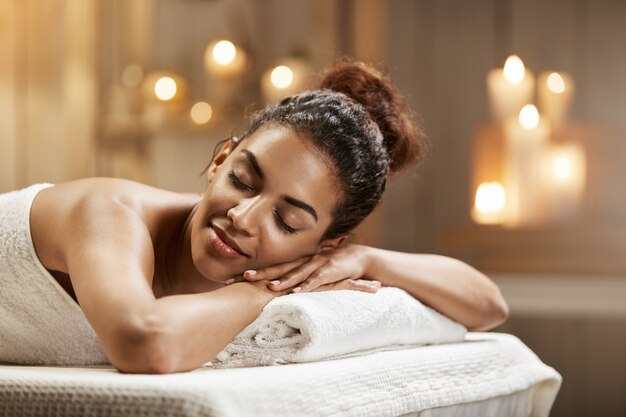 Schöne afrikanische Frau, die sich im Spa-Resort mit geschlossenen Augen ausruht.