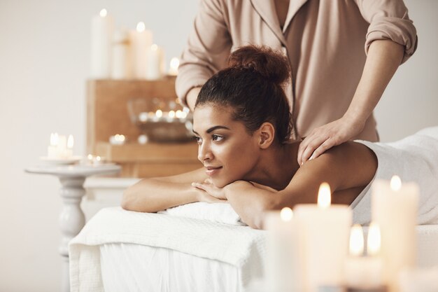 Schöne afrikanische Frau lächelnd, die Massage im Kurort genießt.