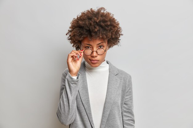 Schöne Afroamerikanerin schaut aufmerksam durch runde Brille