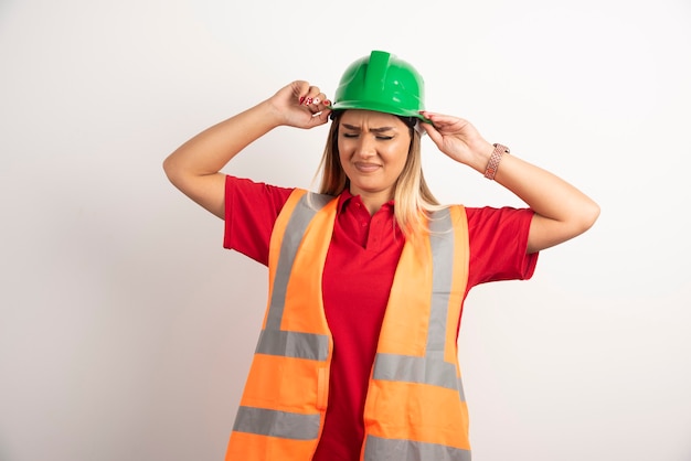 Schöne Arbeitskraftfrau, die einen grünen Helm auf weißem Hintergrund trägt.