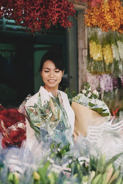 Schöne asiatische Dame, die Blumen im Blumengeschäft wählt