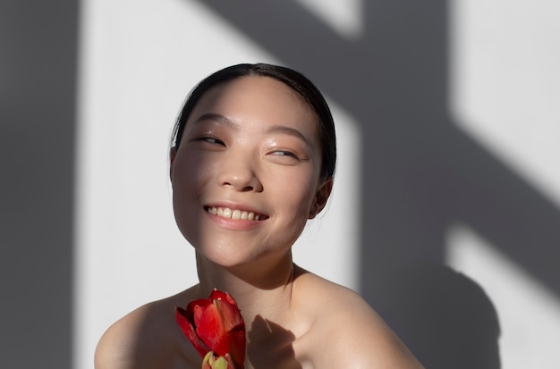 Kostenloses Foto schöne asiatische frau, die eine rose mit perfekter haut hält