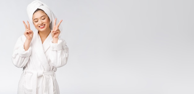 Schöne asiatische Frau, die Friedenszeichen oder zwei Finger mit dem glücklichen Gefühl lokalisiert über weißem Hintergrund zeigt