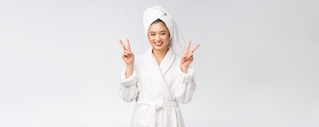 Schöne asiatische Frau, die Friedenszeichen oder zwei Finger mit dem glücklichen Gefühl lokalisiert über weißem Hintergrund zeigt
