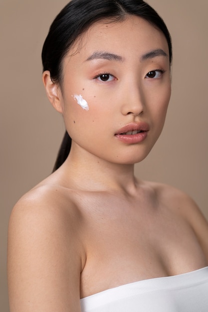 Schöne asiatische Frau, die Hautbehandlung anwendet