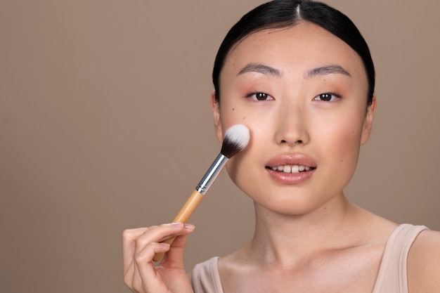 Schöne asiatische Frau, die Make-up anwendet