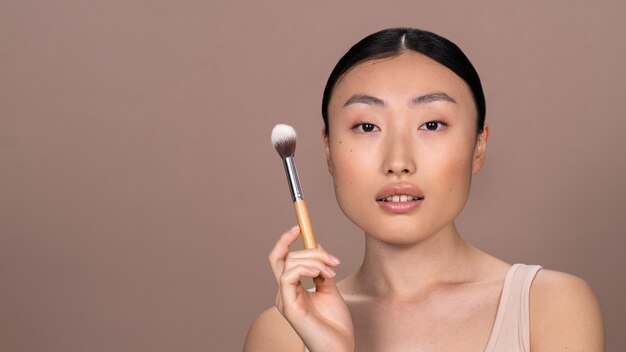 Schöne asiatische Frau, die Make-up anwendet