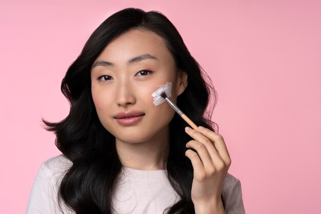 Schöne asiatische Frau, die Make-up anwendet