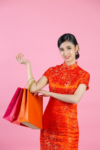 Schöne asiatische Frau glückliches Lächeln und Einkaufen im chinesischen Neujahr auf rosa Hintergrund.