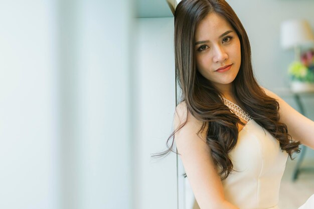 Schöne asiatische Frau mit braunem, langem Haarporträt, weißem Kostüm, Liftstyle-Konzept