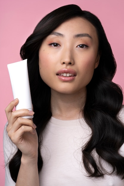 Schöne asiatische Frau mit Gesichtscreme