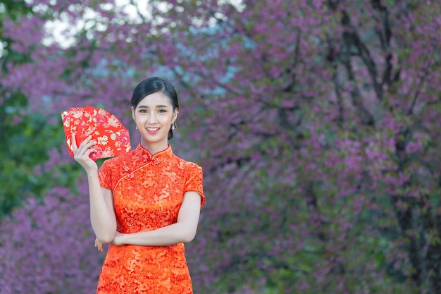 Kostenloses Foto schöne asiatische frau zeigt etwas und nimmt rote umschläge im chinesischen neujahr