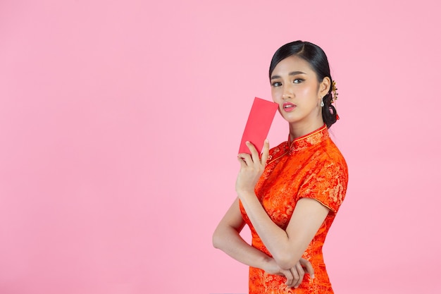 Schöne asiatische Frau zeigt etwas und nimmt rote Umschläge im chinesischen Neujahr