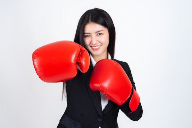 schöne asiatische Geschäftsfrau, die in der Hand einen Boxhandschuh und einen Anzug trägt