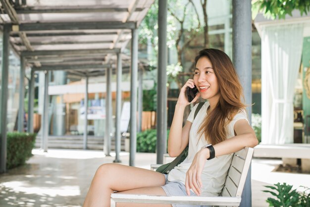 Schöne asiatische junge Frau, die Smartphone für die Unterhaltung verwendet