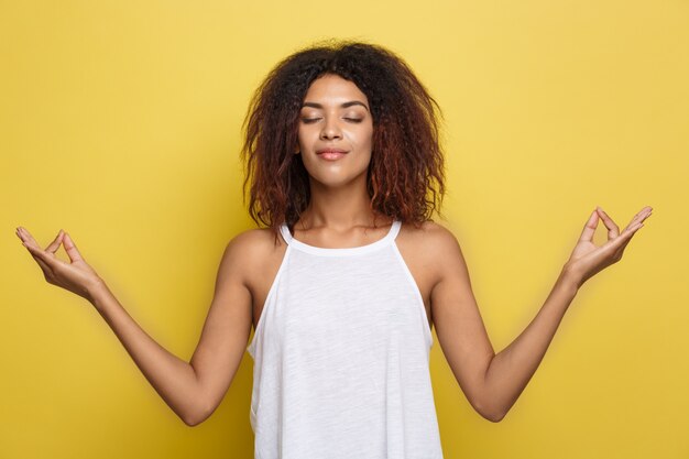 Schöne attraktive African American Frau mit trendy Brille Posting über gelb Studio Hintergrund. Text kopieren