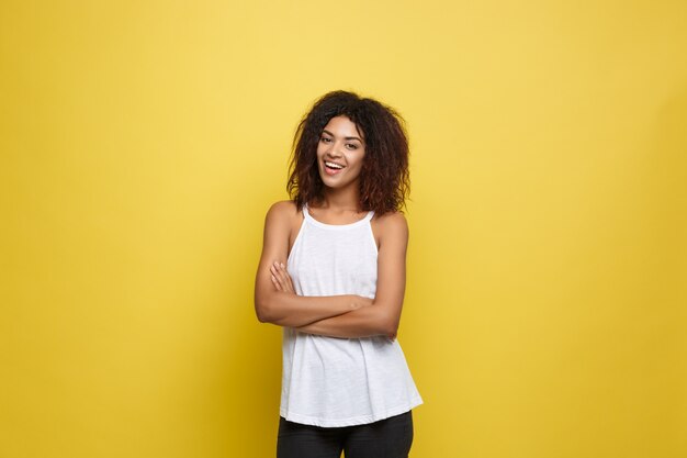 Schöne attraktive afroamerikanische Frau Posting Spiel mit ihrem lockigen Afro Haar. Gelb Studio Hintergrund. Text kopieren