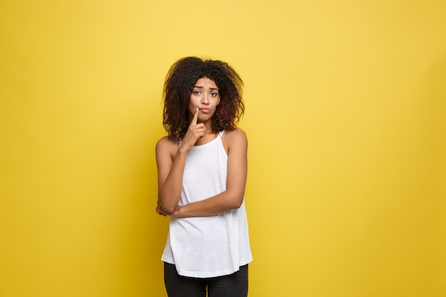 Schöne attraktive afroamerikanische Frau Posting Spiel mit ihrem lockigen Afro Haar. Gelb Studio Hintergrund. Text kopieren