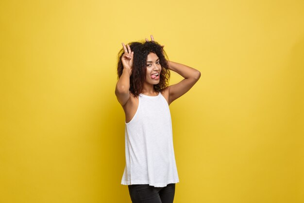 Schöne attraktive afroamerikanische Frau Posting Spiel mit ihrem lockigen Afro Haar. Gelb Studio Hintergrund. Text kopieren