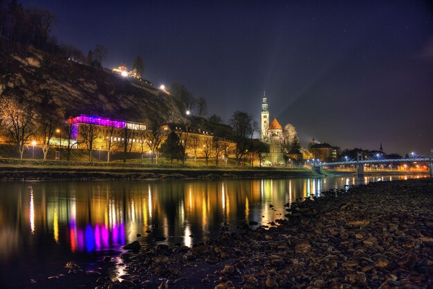 Schöne Aufnahme der historischen Stadt Salzburg, die sich nachts im Fluss spiegelt