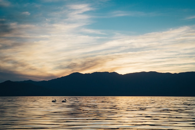 Schöne Aufnahme des Meeres mit dunklen Hügeln und erstaunlichem Himmel bei Sonnenuntergang