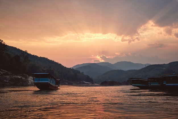 Schöne Aufnahme des Mekong mit Booten im Vordergrund bei Sonnenuntergang in Pak Beng, Laos