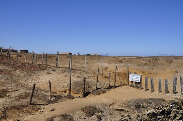 Schöne Aufnahme einer Wüste in Chile durch einen Zaun mit Gebäuden im Hintergrund getrennt