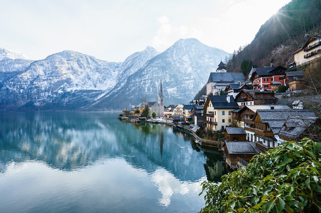 Schöne Aufnahme eines kleinen Dorfes, umgeben von einem See und schneebedeckten Hügeln