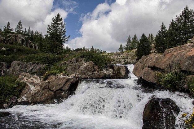 Schöne Aufnahme eines kleinen Wasserfalls mit Felsformationen und Bäumen um ihn herum an einem wolkigen Tag