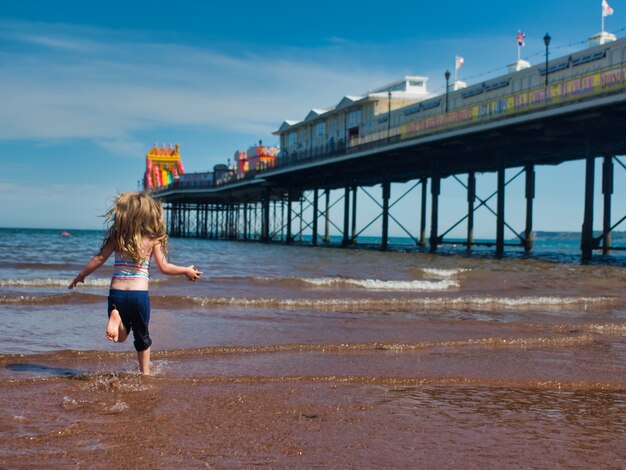 Schöne Aufnahme eines Mädchens, das in die Szene in Paignton Beach, England, rennt