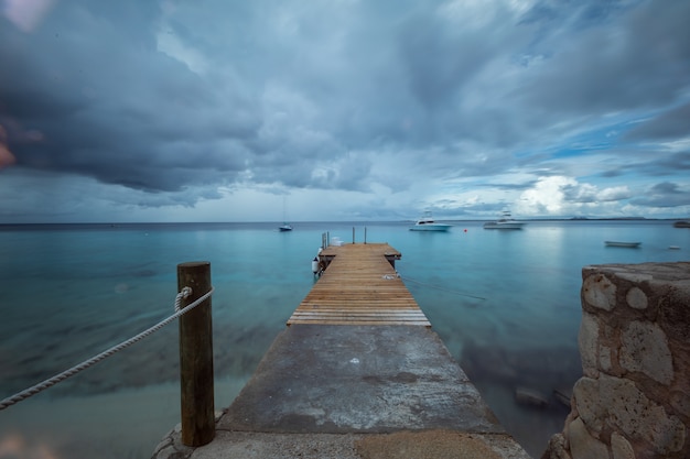 Schöne Aufnahme eines Piers, der zum Ozean unter dem düsteren Himmel in Bonaire, Karibik führt