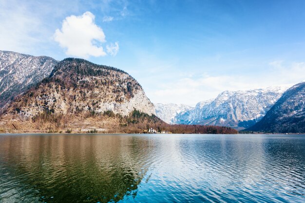 Schöne Aufnahme eines ruhigen Sees, umgeben von Hügeln unter blauem Himmel