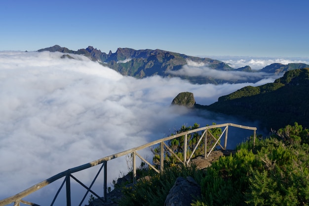 Schöne Aufnahme von grünen Bergen und Hügeln bedeckt in weißen Wolken in einem klaren Himmel