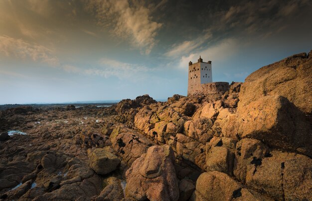 Schöne Aufnahme von Klippen und Felsen mit einer Festung oben unter einem blauen Himmel