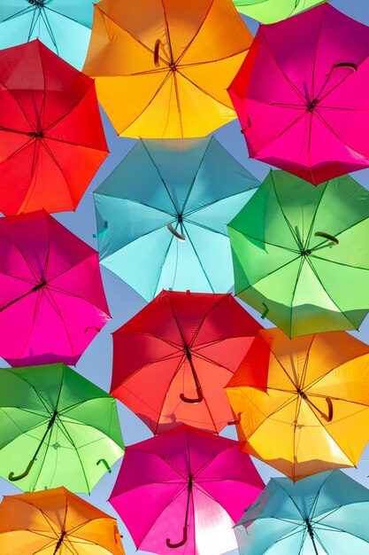 Schöne Aufnahme von mehrfarbigen schwimmenden Regenschirmen gegen den blauen Himmel