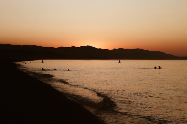 Schöne Aufnahme von Menschen, die im Wasser nahe der Küste mit klarem Himmel schwimmen