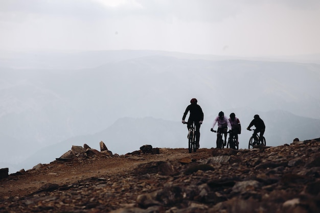 Schöne aufnahme von radfahrern auf einem berg mit bewölktem himmel im hintergrund