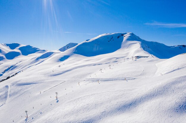 Schöne Aufnahme von schneebedeckten Bergen mit Skigebieten auf ihren Pisten unter blauem Himmel