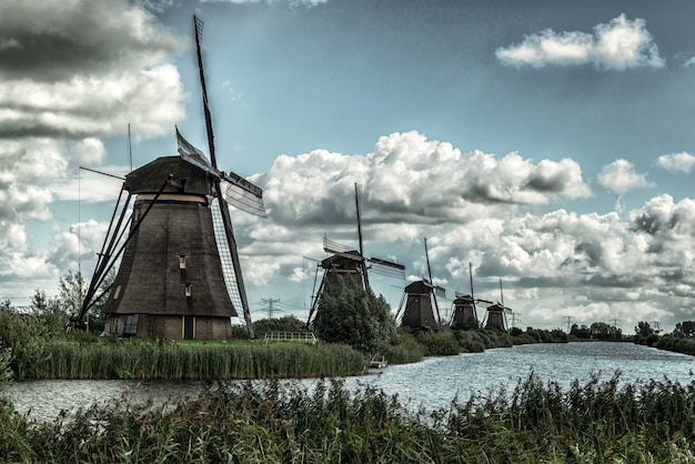 Schöne Aufnahme von Windmühlen, die sich im See unter dem atemberaubenden bewölkten Himmel spiegeln