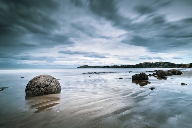 Schöne Aussicht auf das Meer mit Felsen am Ufer und Bergen in der Ferne